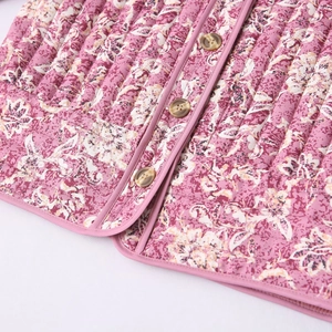Close-up of pink floral quilted jacket featuring marble-patterned buttons and piping