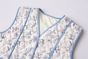 Detail of V-neck quilted cotton vest with purple floral print and light blue piping
