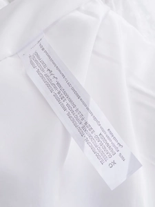 Detail view of the 100% cotton fabric care label on a French-style white mini dress