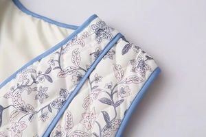 Macro shot of diamond-quilted vest featuring blue floral print and sky blue binding