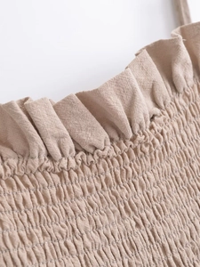 Detailansicht der elastischen Smok-Textur und Rüschen am haferfarbenen Midi-Kleid