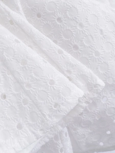 Detail of white eyelet lace fabric with intricate floral embroidery and hollow cutouts