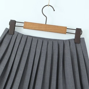Close-up of pleated dark grey high-waisted skirt with detailed waist ribbon and sharp folds