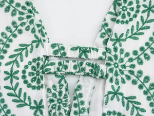 Detailed macro view of white fabric with green floral embroidery and elastic pleated structure