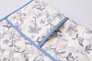 Detail of diamond-quilted cotton vest featuring retro floral patterns and navy blue trim