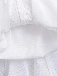 Detailed macro view of white eyelet embroidery on a lightweight cotton summer dress fabric