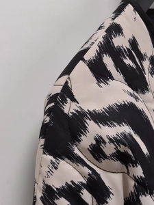 Vue détaillée d'une veste matelassée à imprimé abstrait noir et blanc avec bordure finie