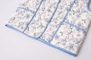 Close-up of floral quilted cotton vest with blue piping and round white buttons