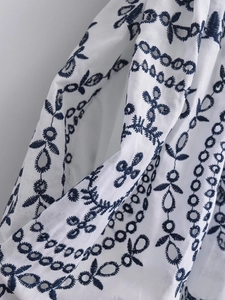 Macro detail of white cotton fabric with navy embroidery and hollow-out cutwork design
