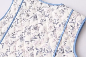 Close-up of quilted floral cotton vest showing delicate blue edging and vintage flower pattern