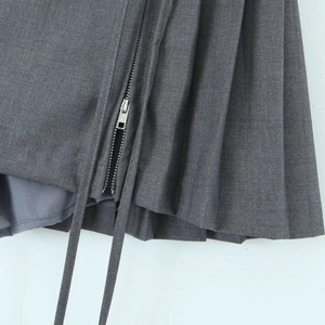 Detail view of dark grey pleated skirt with metal zipper and high-quality fabric texture