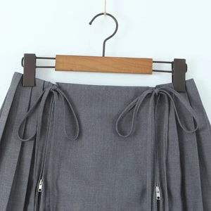 Close-up of high-waisted pleated skirt featuring side zippers and ribbon bow accents
