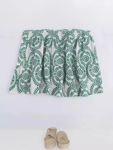 White mini dress with green vine embroidery and elastic waist on a plain background