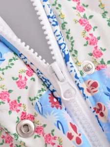 Detail of floral quilted jacket featuring white resin zipper and silver snap buttons