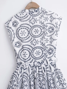 Detail view of white sleeveless dress with blue geometric floral embroidery and eyelet lace