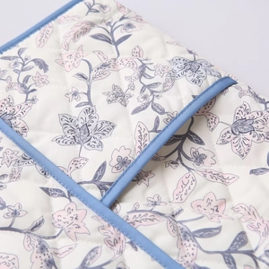 Close-up of quilted floral print fabric featuring light blue trim and diamond texture