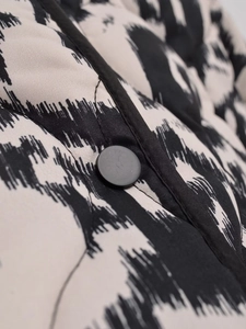 Gros plan sur le bouton noir mat et le motif animalier de la veste en coton matelassée