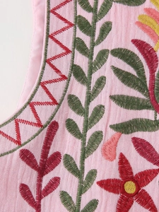 Detailed close-up of intricate multi-colored floral embroidery on pink cotton linen vest
