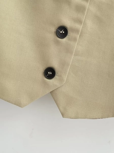 Nahaufnahme der beigen Twill-Stoffstruktur und mattschwarzen Knöpfe an einer Weste