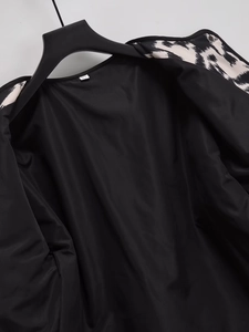 Détail intérieur d'une veste noire avec col imprimé zèbre et étiquette de taille XS visible