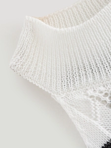 Detail of high neck ribbed knit with delicate openwork pattern on white sleeveless dress