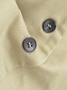 Makrodetail der Khaki-Köperbindung und mattschwarzen Knöpfe an einem sommerlichen Zweiteiler