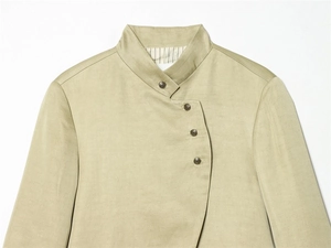 Detail of light green high-neck linen jacket featuring vintage embossed metal buttons