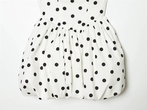 Detail of polka dot mini dress featuring pleated waist and bubble hem silhouette