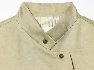 Detail of high collar jacket with layered asymmetric flap and vintage bronze buttons
