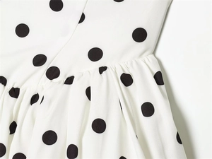 Detail of polka dot dress fabric showing high-quality stitching and elegant pleats
