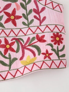 Close-up of pink cotton fabric with detailed floral embroidery and geometric patterns