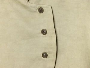 Detailed macro view of khaki cotton linen fabric texture and vintage sunburst bronze buttons