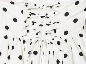 Detailed close-up of corset-style lace-up back on a black and white polka dot dress