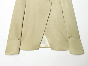 Detail of sage green linen blazer sleeve with vintage metal buttons and striped lining