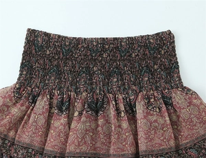 Detail view of smocked elastic waistband and bohemian honeycomb print on layered skirt