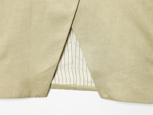 Detail of light olive blazer with linen texture, striped lining and back slit vent