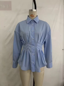 Détail d'une chemise bleu clair avec taille plissée et coupe à basque sophistiquée
