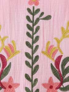 Macro detail of delicate floral embroidery on pink cotton-linen texture fabric