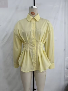 Détail des plis à la taille et de la coupe cintrée sur une chemise jaune à manches