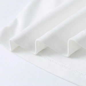 Detailed macro view of white knitted fabric showing precise double-stitch hem and soft texture