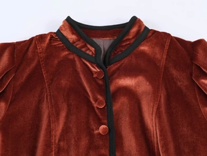 Detail of velvet blazer neckline featuring black braided trim and matching buttons