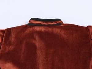 Detail of rust velvet blazer collar with black contrast trim and sleek fabric texture