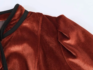 Detailed close-up of brick red velvet jacket with black ribbed collar and puff sleeves