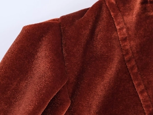 Detailed macro view showing the texture and stitching of dark brown corduroy blazer fabric