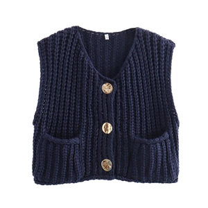 Detail of navy knit vest with gold buttons and two square patch pockets in macro view
