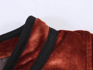 Macro shot of dark red velvet fabric with premium black braided trim and texture