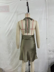 Detail of halter neck bow tie and open back design on a silky green satin dress