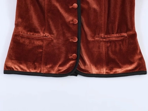 Detail of rust brown velvet blazer with black ribbed trim and fabric covered buttons