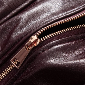 Detail of rose gold metal zipper on glossy wine red faux leather biker jacket