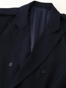 Detailed view of peak lapels, epaulettes, and double-breasted buttons on navy blazer